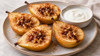 Quattro pere al forno con noci e miele, accanto ad uno yogurt naturale