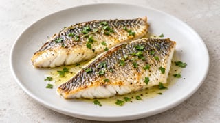 Dos filetes de dorada cocidos con piel dorada y perejil
