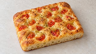 Piccola focaccia dorata con pomodori e origano negli incavi