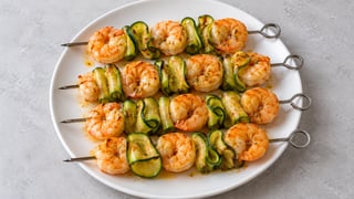 Brochettes métalliques aux crevettes cuites et rubans de courgette