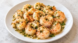 Langostinos de ajo cocidos con perejil y jugo de limón en un plato blanco