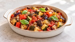 Melanzana cotta, zucchine e pepe in pezzi di succo di pomodoro con poche foglie di basilico in un unico piatto