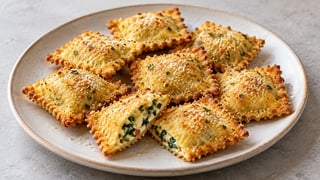 Ravioli carré doré avec fines herbes et miettes de fromage sur une assiette