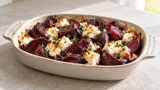 Cuñas de remolacha roja cocida en rojo oscuro con trozos de feta suaves y perejil picado en un plato poco profundo