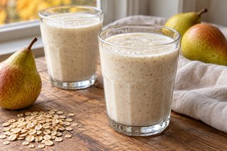 Zwei Gläser mit cremigem hellem Birnen-Buttermilch-Smoothie und feinen Haferflockenpartikeln