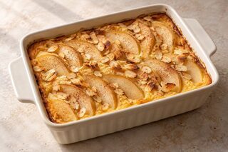 Goldener Polenta-Auflauf in einer kleinen Form, belegt mit Birnenspalten und gerösteten Mandelblättchen