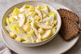 Endibias claras con láminas de pera y dados de Gouda en aliño de yogur junto a pan de centeno