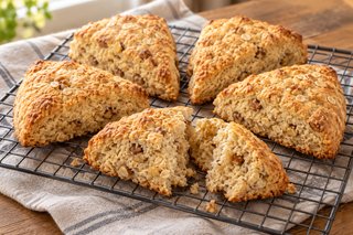 Scones triangulares dorados de avena y nueces con superficie mate y trocitos de nuez visibles