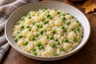 Risotto clair crémeux avec petits dés de chou-rave et petits pois verts dans une assiette creuse