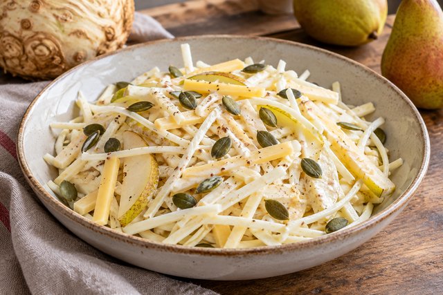 Feine helle Selleriestifte mit Birnenstücken, Goudastreifen und grünen Kürbiskernen in hellem Joghurt-Dressing