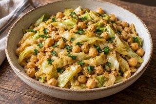 Gegarte Spitzkohlstreifen und Kichererbsen in heller Erdnusssauce mit Petersilie in einer Schale