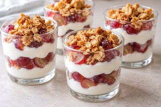 Verrines de crème blanche au quark, raisins rouges coupés et morceaux dorés de croquant d’avoine